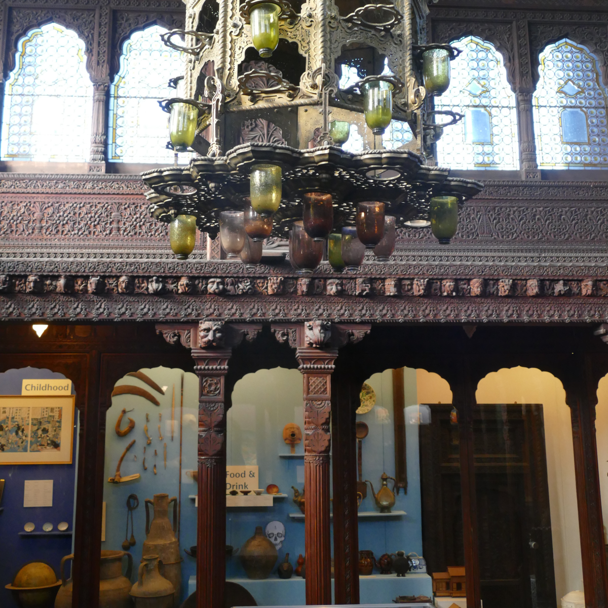 Interior of Durbar Hall, Hastings, with ornate carved wood, hanging lanterns and museum displays including a Grey Owl exhibit.